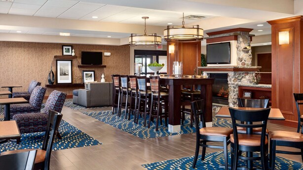 Un hall d’hôtel comprenant un bar, des espaces aménagés avec des sièges et un téléviseur fixé au mur.