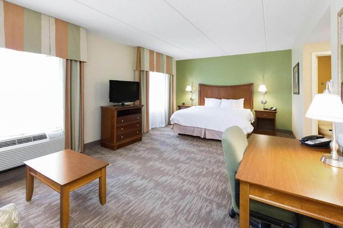 Una habitación de hotel con una cama, un televisor en una cómoda, un escritorio y una silla.