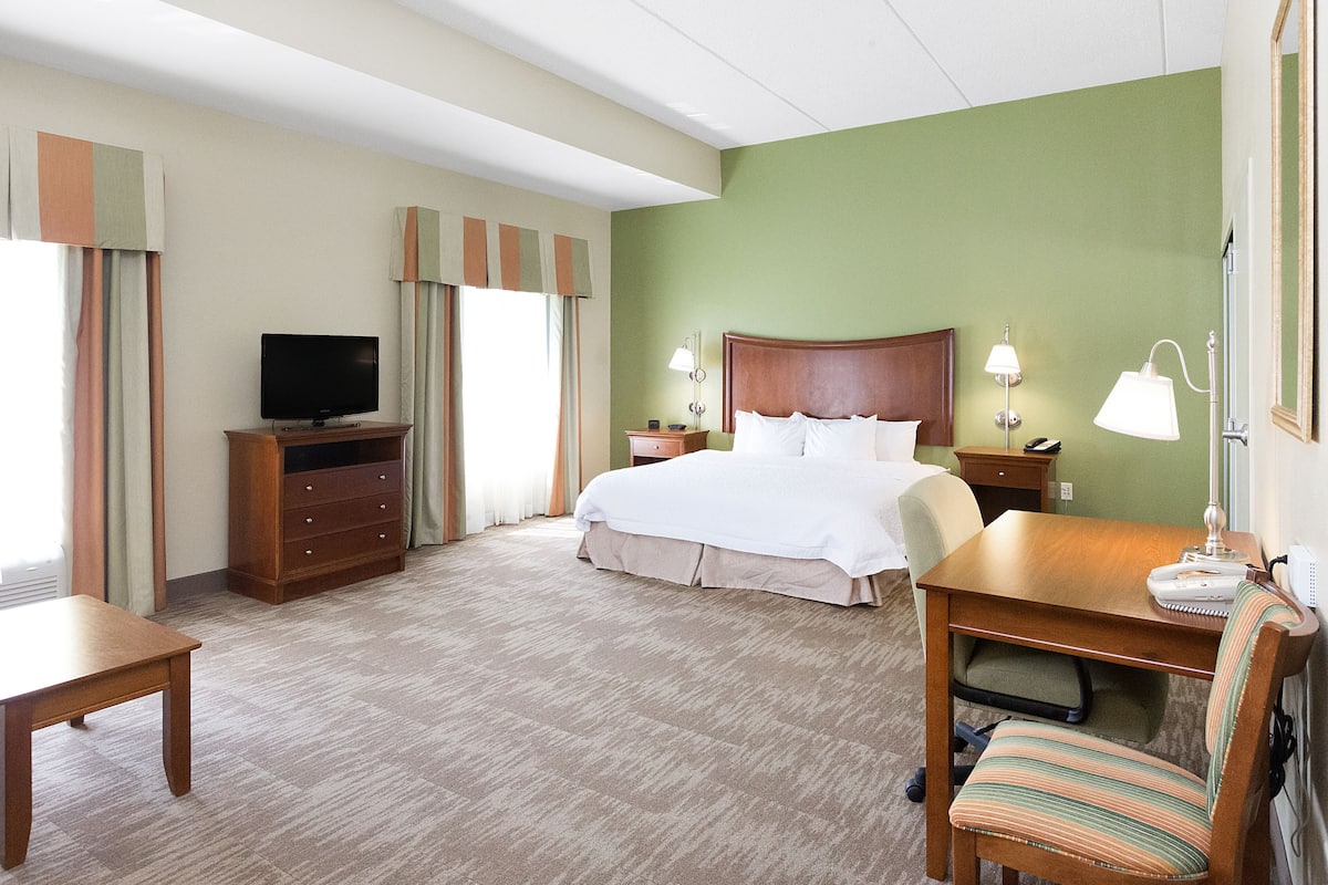 Una habitación de hotel con una cama, un escritorio, una silla, un televisor y una lámpara.