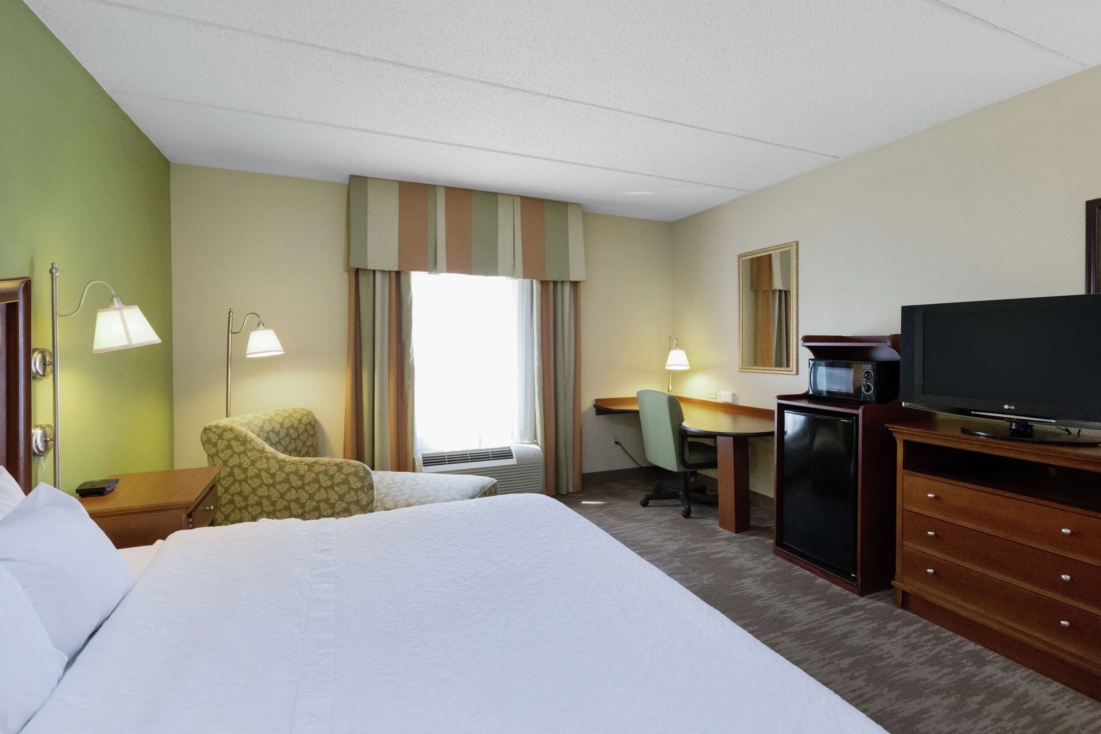 Een hotelkamer met een groot bed, een bureau met een computer, een televisie en een stoel.
