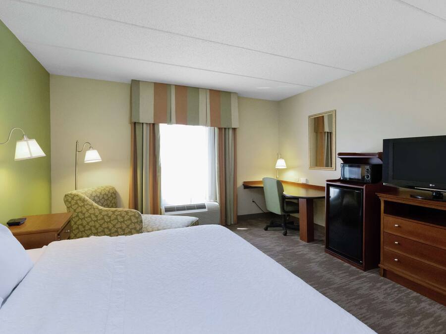 Een hotelkamer met een groot bed, een bureau met een computer, een televisie en een stoel.