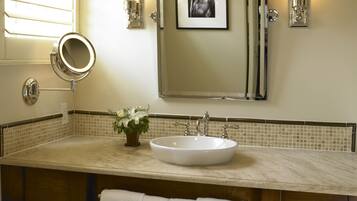 A bathroom with a large sink, a mirror, and a framed picture on the wall.