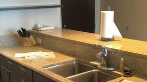 A modern kitchen with dark wooden cabinets, a stainless steel dishwasher, and a double sink. - Pointe 400 by ExecuStay (St. Louis)