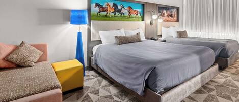 Een hotelkamer met twee bedden, een bank, een lamp en een schilderij van paarden.