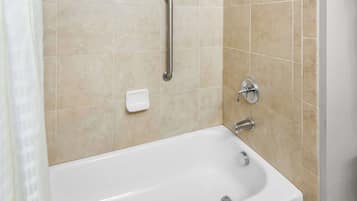 Une salle de bain équipée d’une baignoire, de barres d’appui et d’un porte-savon.