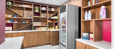 Eine Küche mit Holzausstattung, einem Edelstahlkühlschrank und Regalen voller Snacks und Getränke.