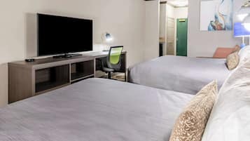 A hotel room with two beds, a TV, a desk with a chair, and a painting on the wall.
