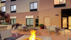 Un patio al aire libre con una chimenea, asientos y un edificio al fondo.