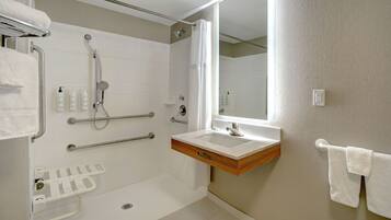 Un baño moderno con ducha, barras de apoyo, lavabo y toallero.