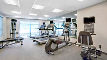 Et fitnesscenter med løbebånd, crosstrainere og styrketræningsudstyr.