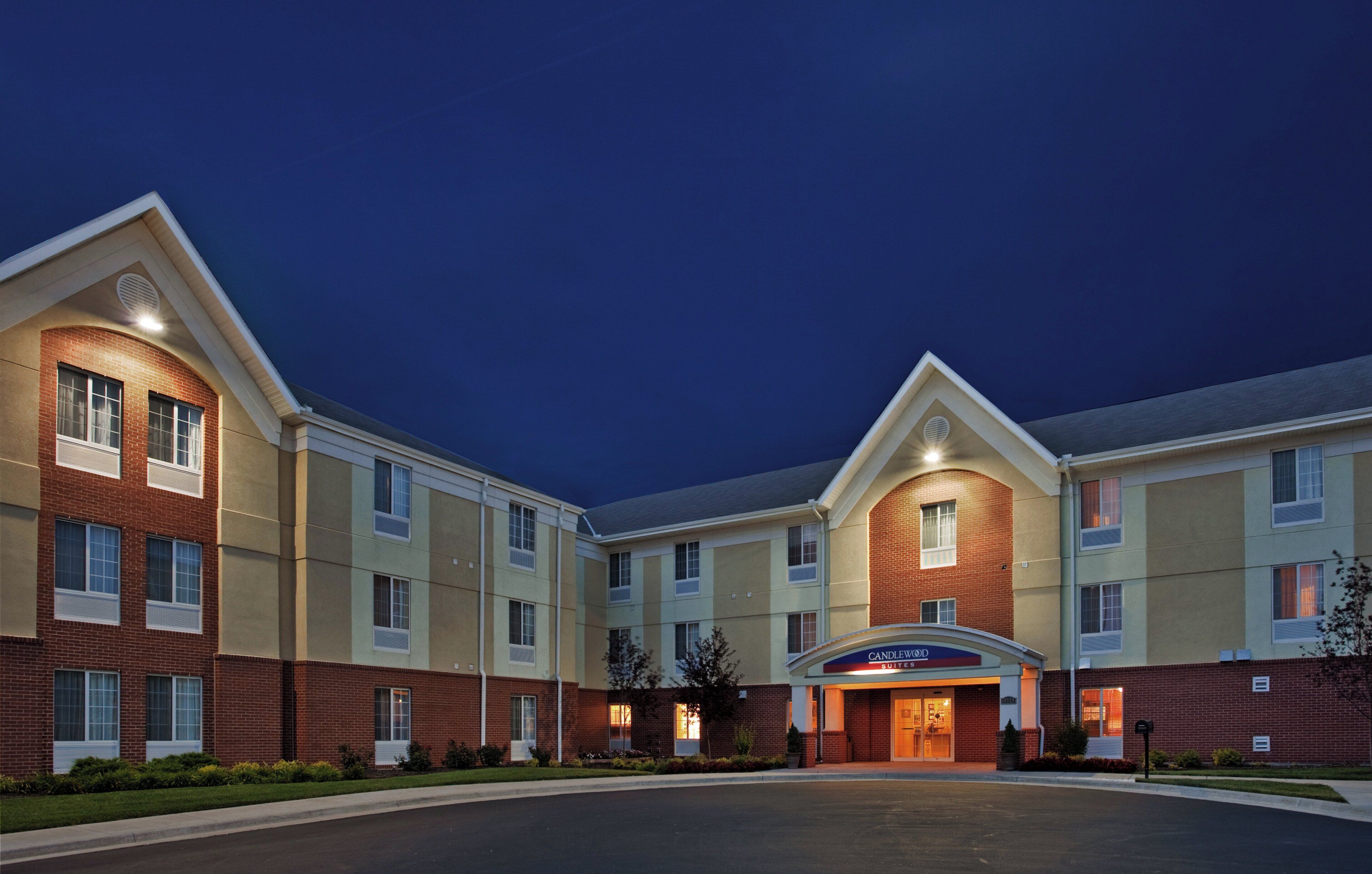 A multi-story hotel with a brick facade, large windows, and a well-lit entrance.