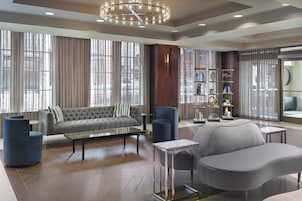 A modern living room with a grey sofa, blue armchairs, a coffee table, and a bookshelf.