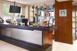 A hotel reception area with a coffee station, a flat-screen TV, and a Starbucks sign.