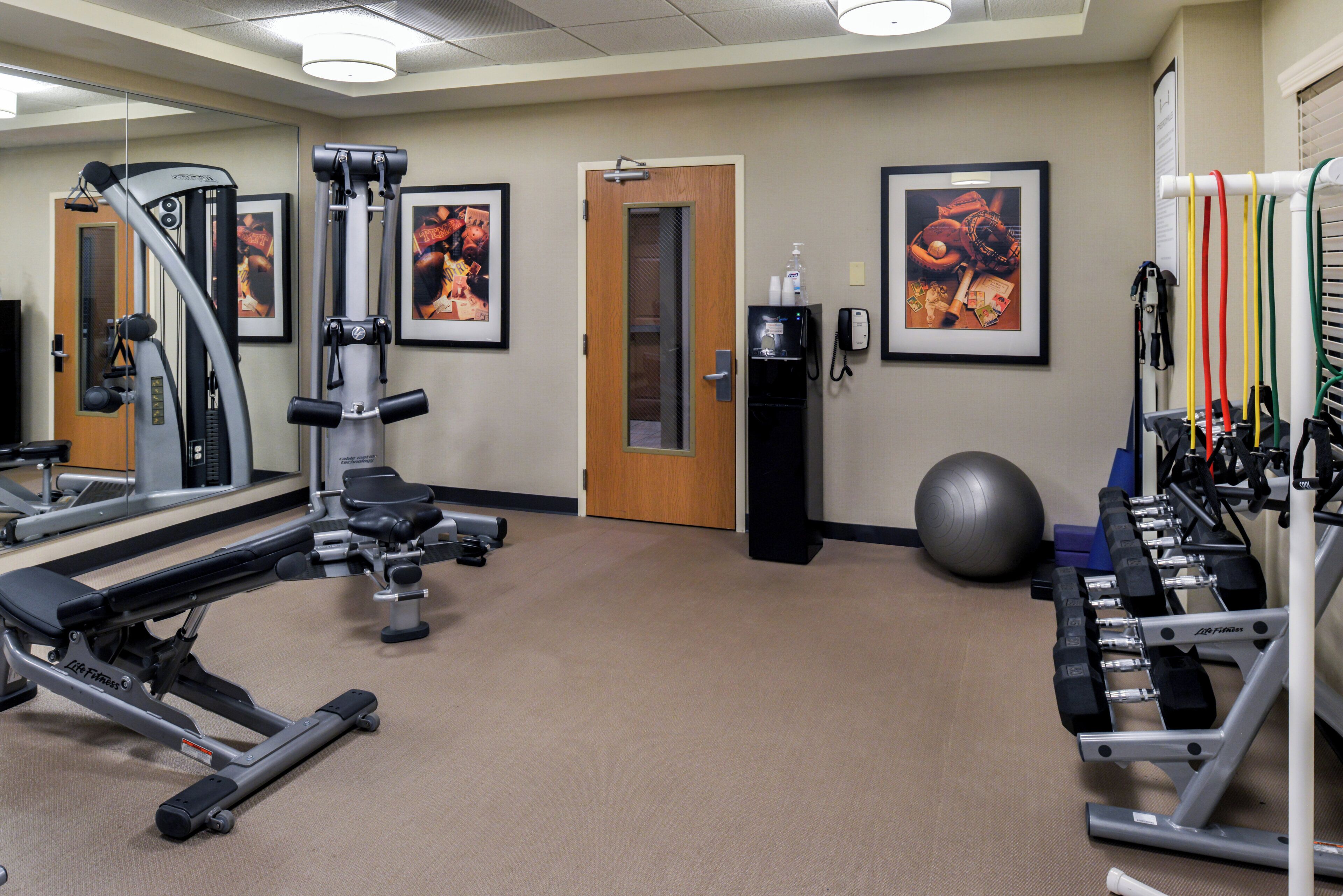 A gym with exercise equipment, a mirror, and framed pictures on the wall.