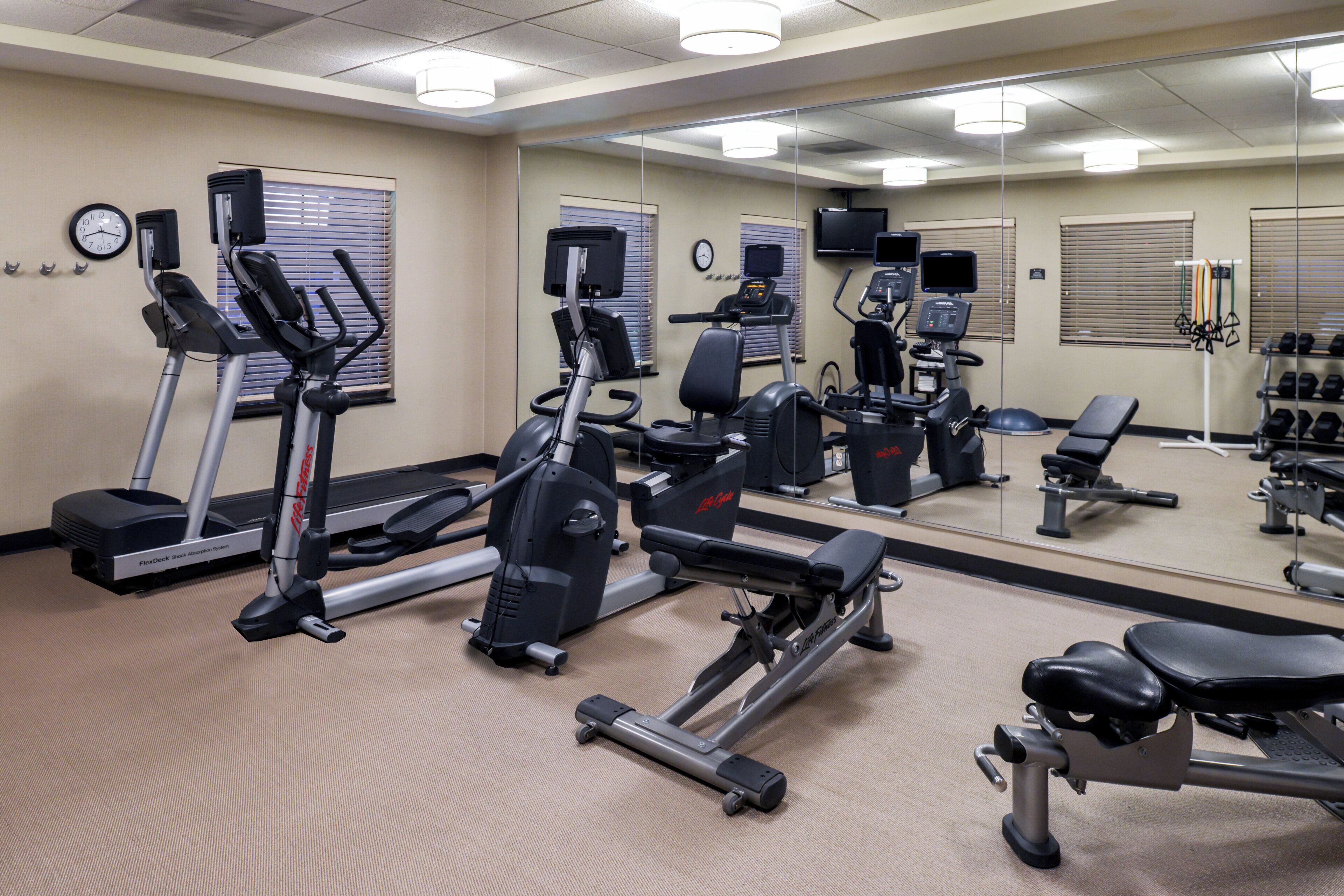 A gym with various exercise equipment including treadmills, an elliptical, and free weights.