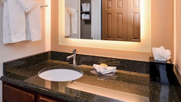 A bathroom with a granite countertop sink, a mirror, and a wooden door.