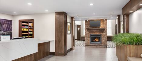 A modern reception area with a stone fireplace, a reception desk, and a plant.