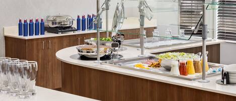 Un buffet proposant une variété de plats, une vitrine réfrigérée et des boissons en bouteille.