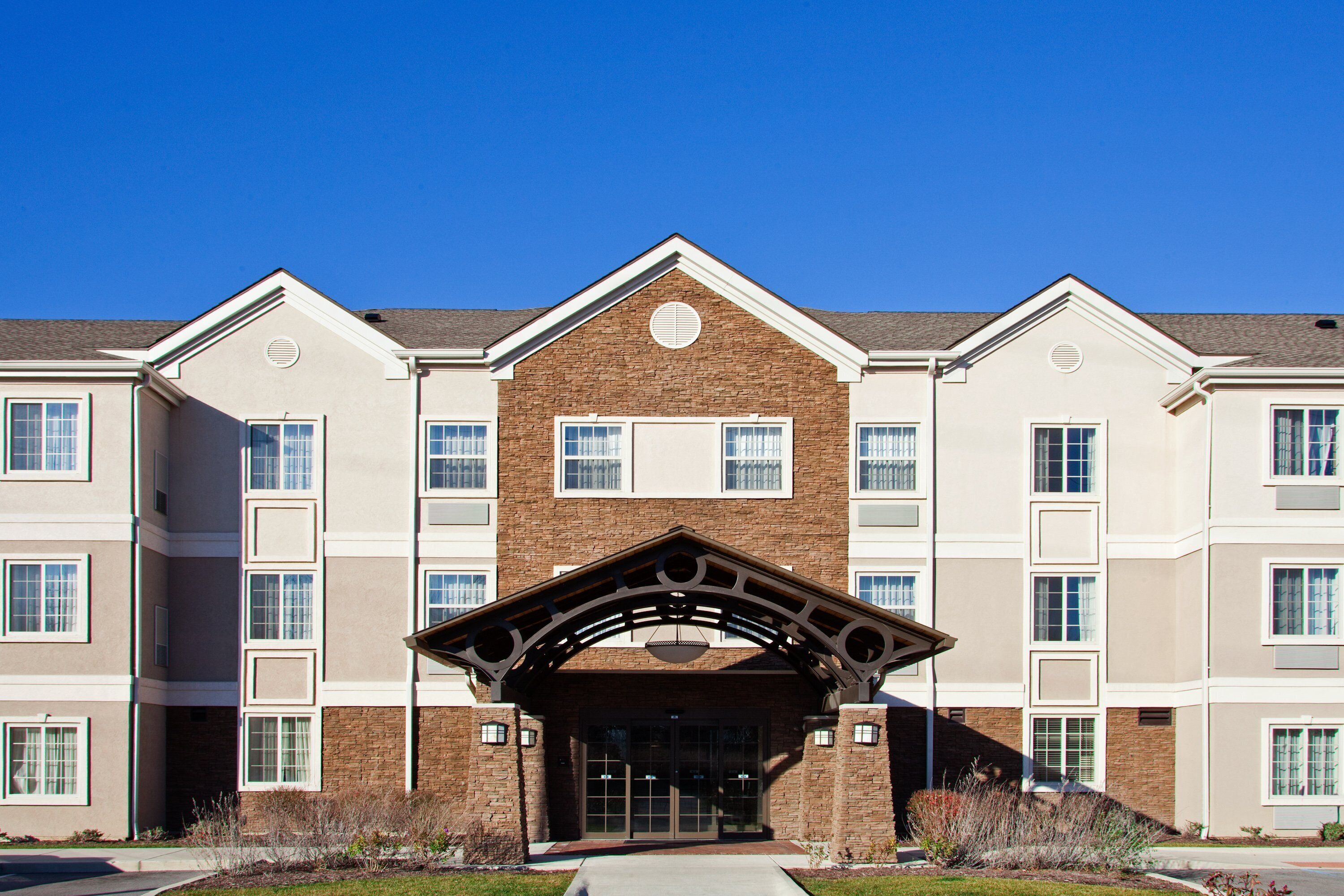 A multi-story building with a central entrance featuring a brick facade and a decorative archway.