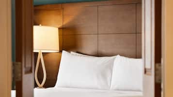 A hotel room with a wooden headboard, a white bed, and a bedside lamp.