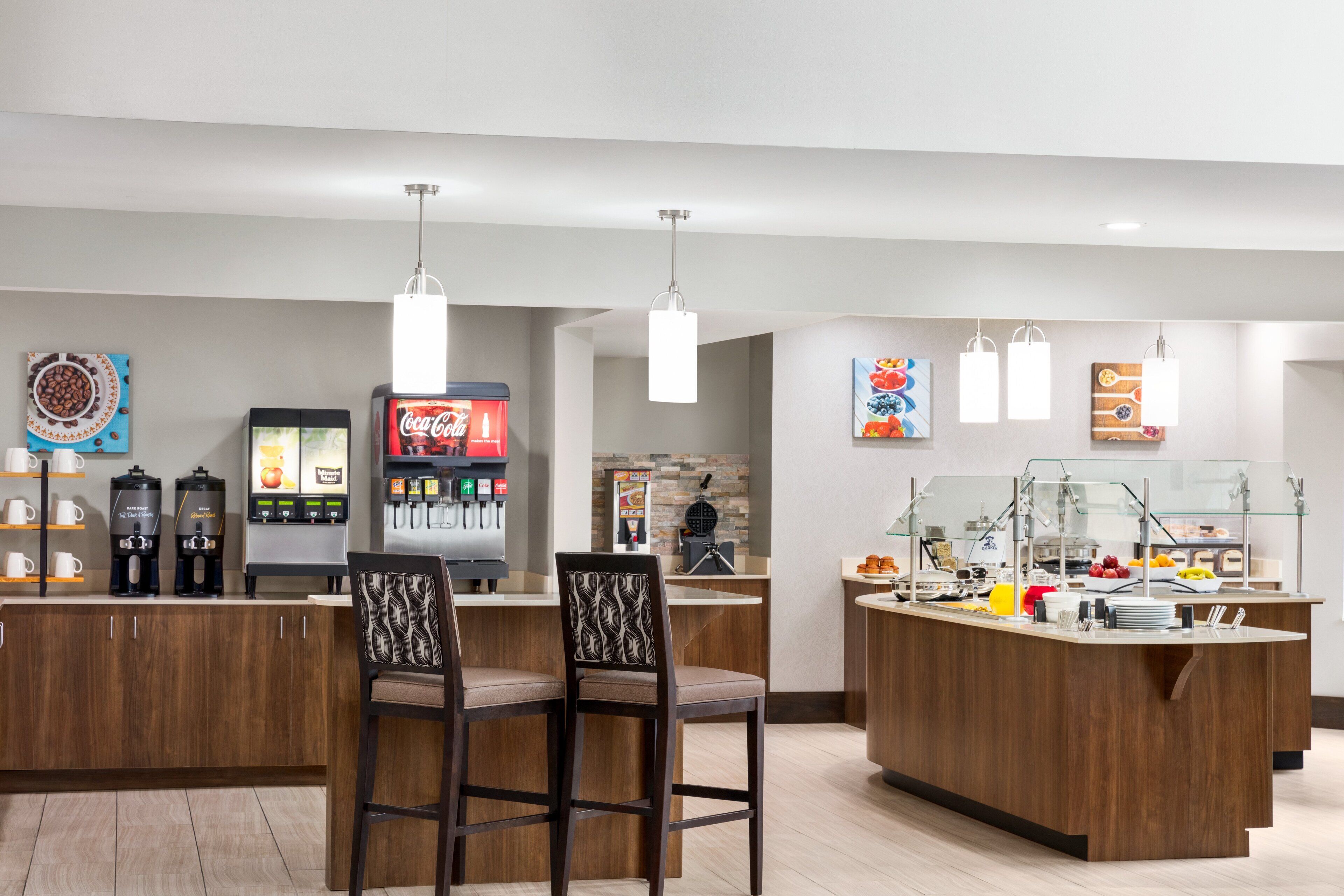 A modern breakfast bar with seating, a coffee machine, and a Coca-Cola refrigerator.