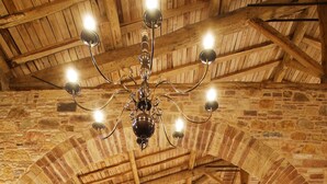 Una sala de conferències amb una taula llarga preparada per a una reunió, parets de pedra, bigues de fusta i un penjallum.