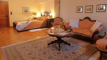 A hotel room with a bed, a sofa, a coffee table with decorative items, a rug, and framed pictures on the wall.