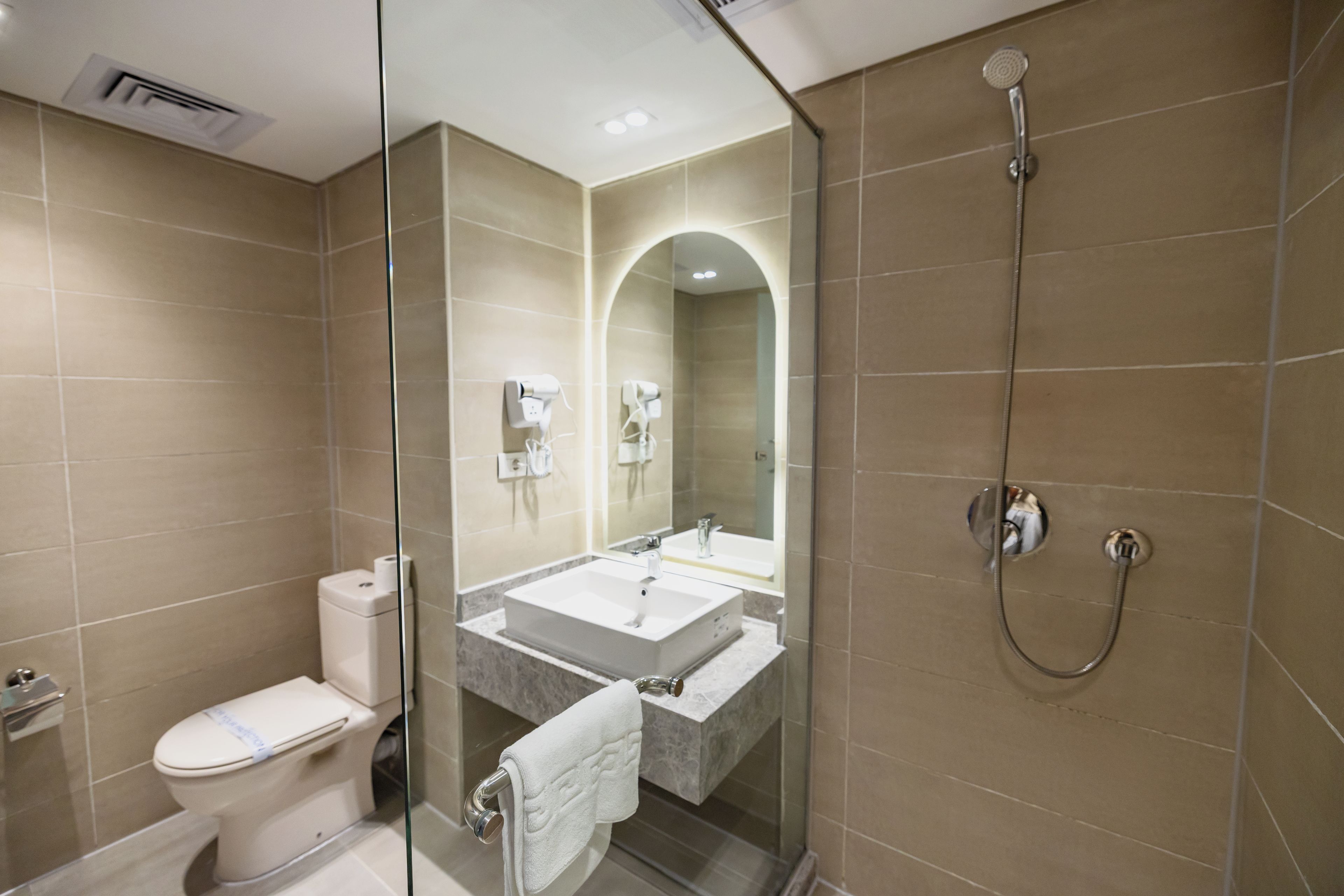 A modern bathroom with a glass partition, a toilet, a sink with a mirror, and a shower.