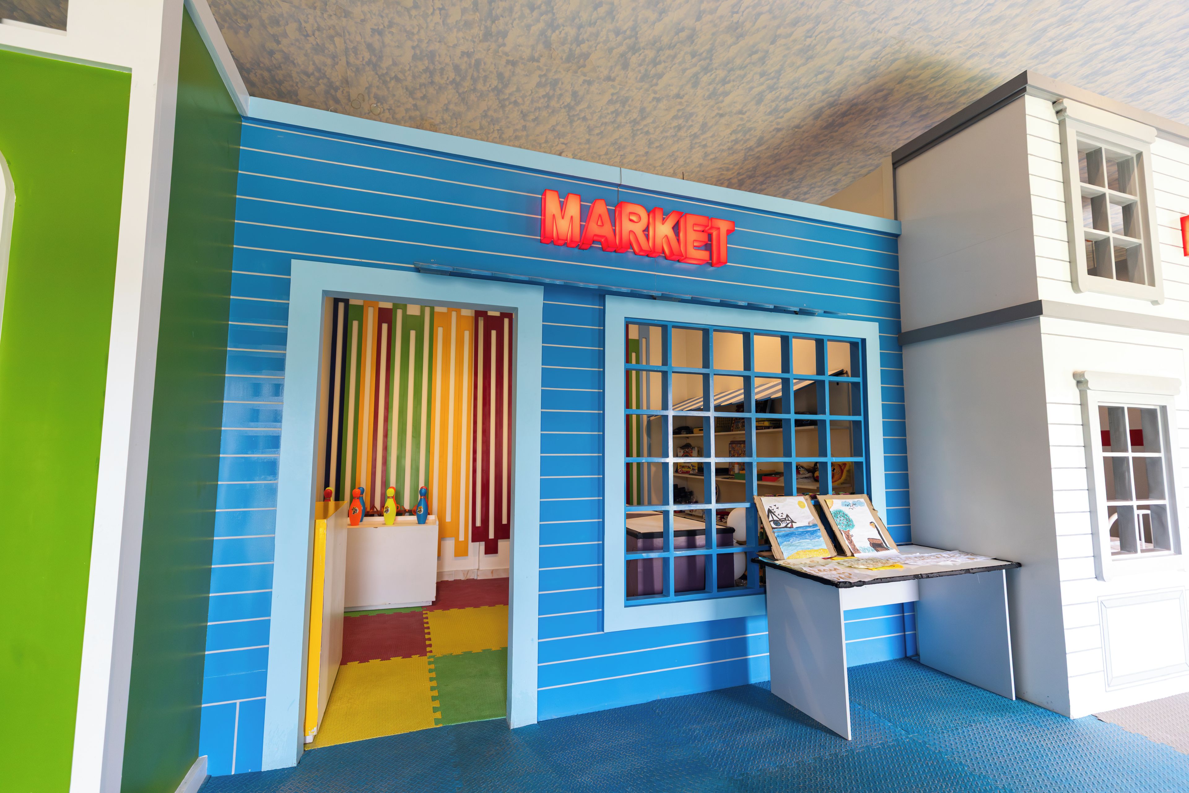 A colorful building with a 'MARKET' sign, a window display, and a door with colorful curtains.