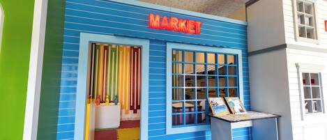 A colorful building with a 'MARKET' sign, a window display, and a door with colorful curtains.