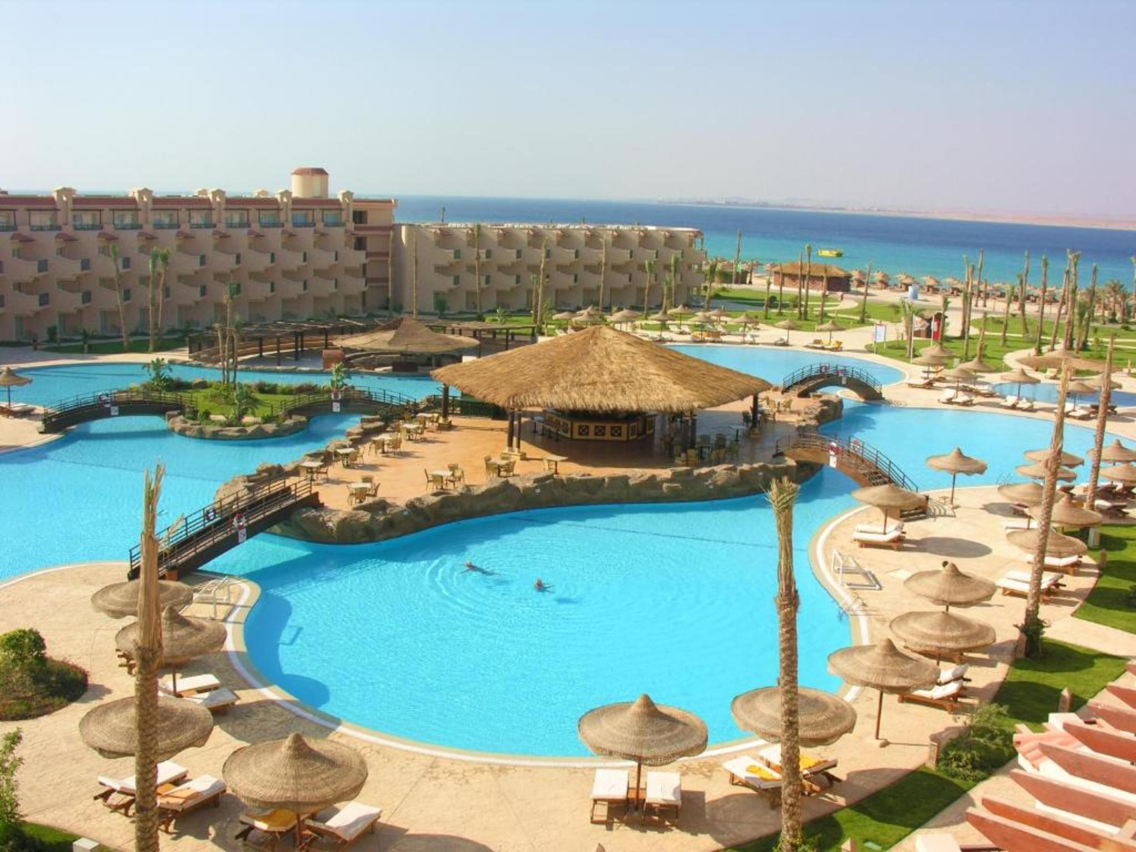 A resort with multiple swimming pools, sun loungers, and thatched-roof structures.