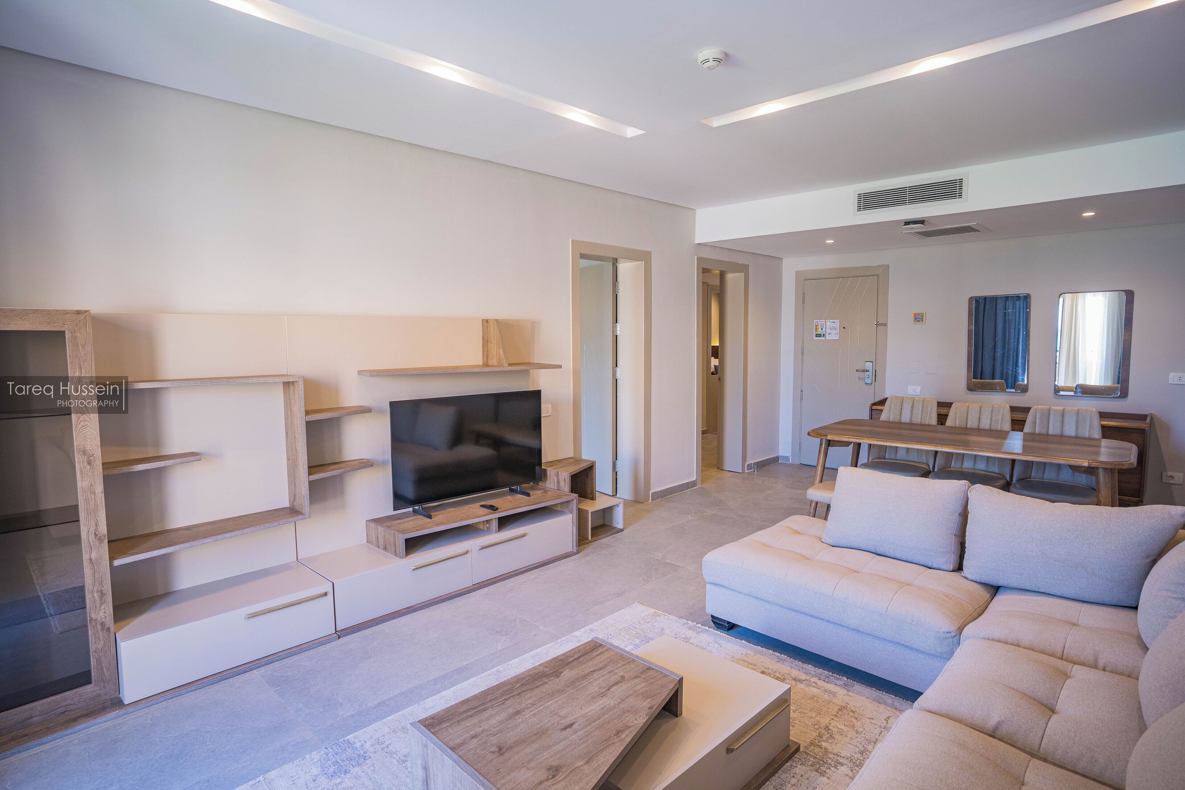 A modern living room with a TV, sofa, and dining area.
