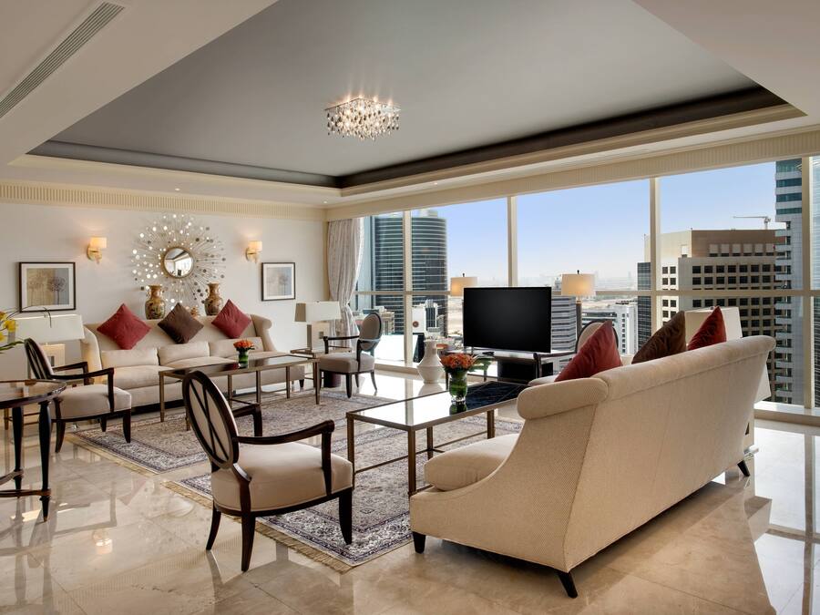 A spacious living room with a large window offering a city view, a chandelier, and a flat-screen TV.