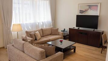 Una sala de estar con un sofá, una mesa de centro, un televisor y un aparador.