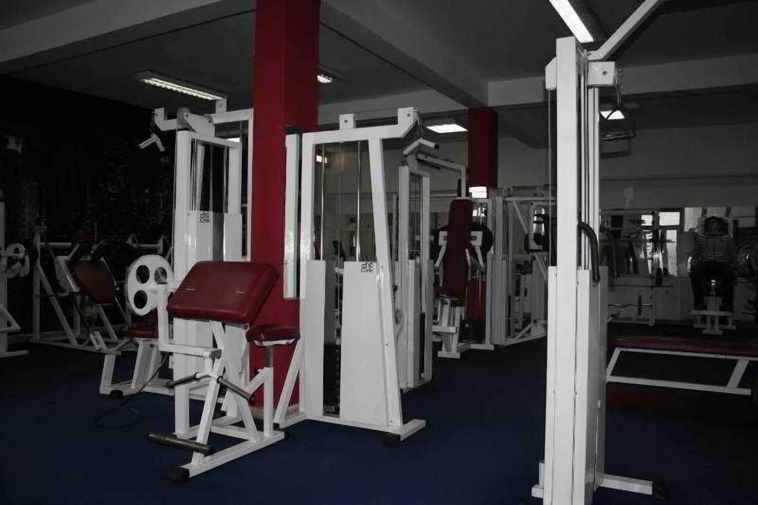 A gym with various exercise machines and a mirror wall.