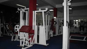 A gym with various exercise machines and a mirror wall.