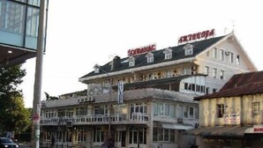 Un hotel con un balcone, diversi piani e una targa.
