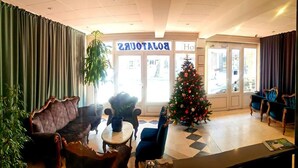 Una hall d'albergo con un albero di Natale, una reception e una zona relax con divani e poltrone.