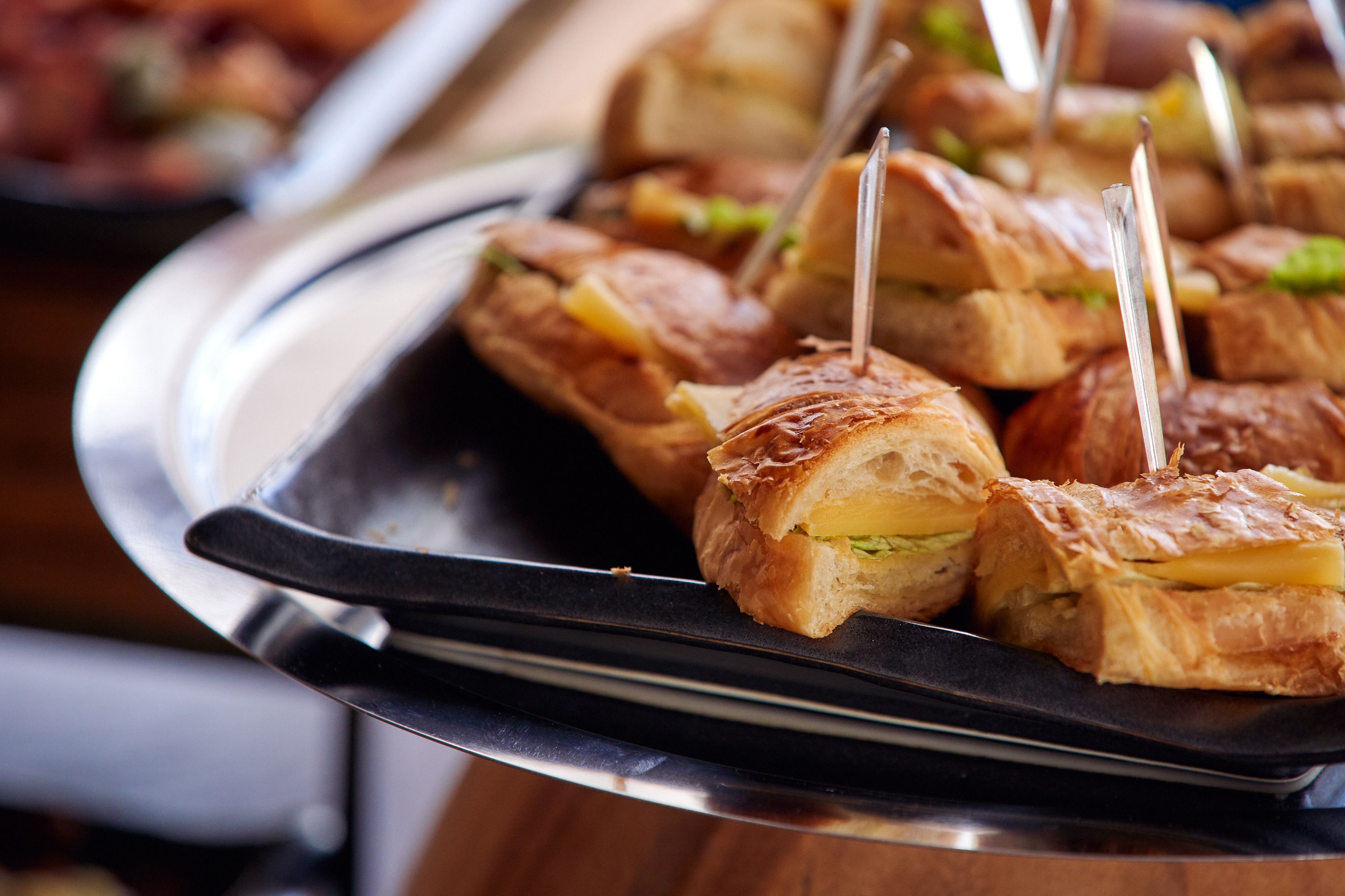 A tray of sandwiches with toothpicks, on a metal serving tray.