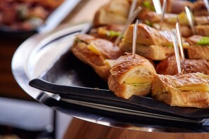 A tray of sandwiches with toothpicks, on a metal serving tray.