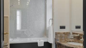 Un baño moderno con bañera, un espejo grande y un lavamanos con encimera de granito.