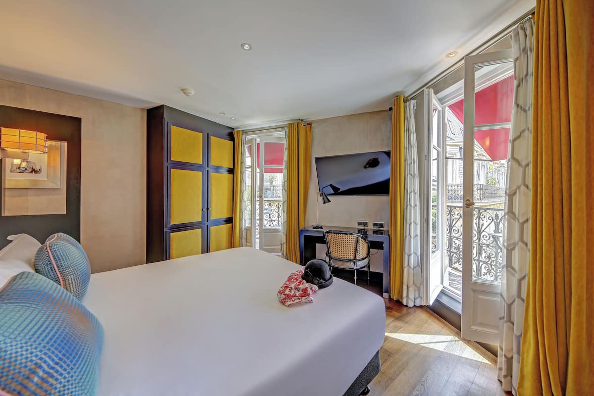 A hotel room with a large bed, a desk, and a TV.