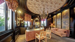 Ein Zimmer mit Schreibtisch, Stühlen, einer Couch und Bildern an den Wänden.