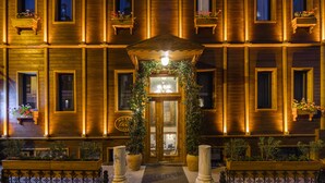 Fachada de hotel con varias ventanas, algunas con jardineras, y una entrada central con una lámpara.
