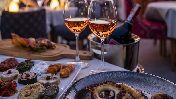 Una mesa preparada para comer, con varios platos y dos copas de vino.
