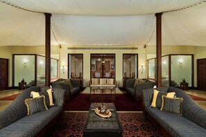 A spacious living area with a large sofa set, a coffee table, and a patterned rug.