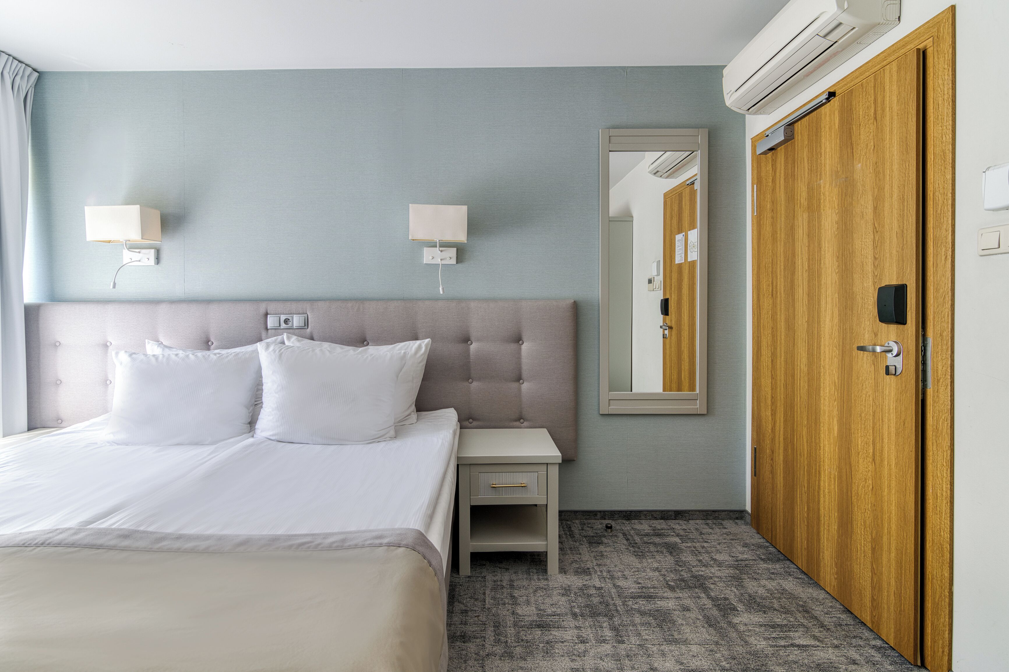 Una habitación de hotel con cama, mesita de noche y armario.
