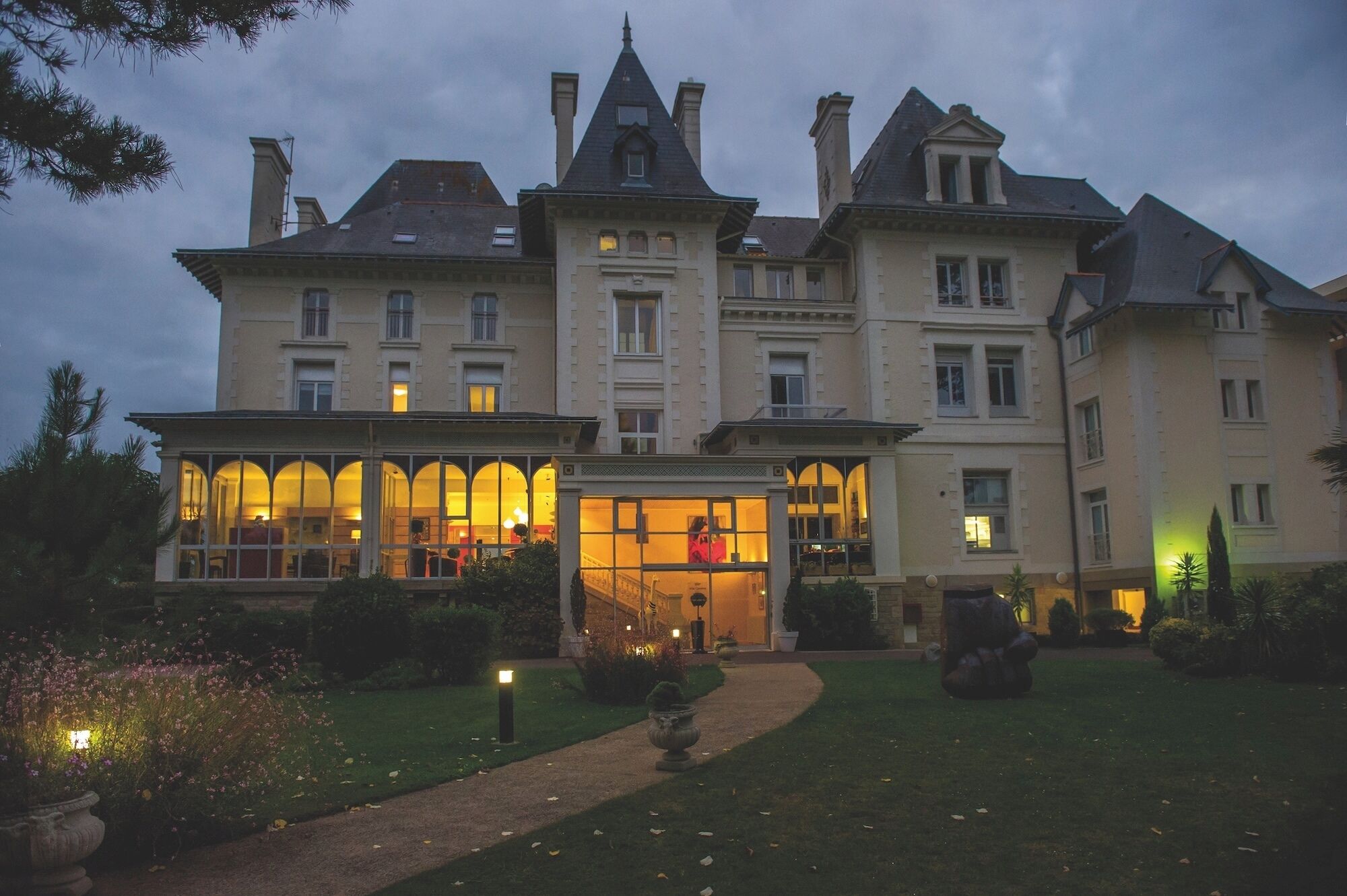 Un grand bâtiment historique à étages, doté d’une entrée principale et d’un jardin bien entretenu.