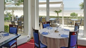 A restaurant with outdoor seating overlooking a beach. - Hôtel Vacances Bleues Villa Caroline (La Baule-Escoublac)