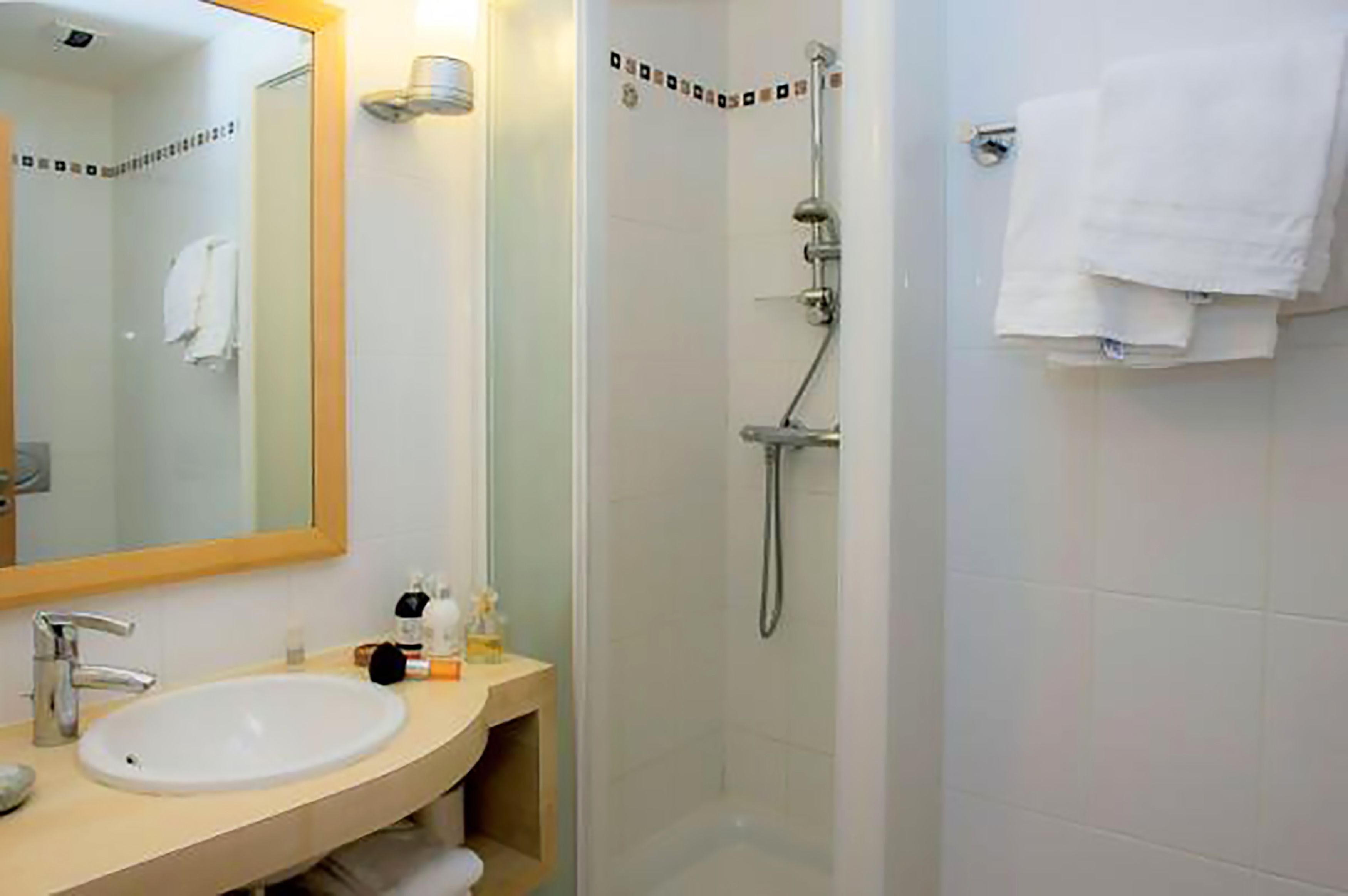 A bathroom with a sink, mirror, and shower.